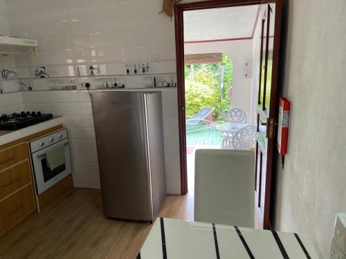 a kitchen with a refrigerator and a door to a patio at Orchid Sunset Guest House in Baie Lazare Mahé