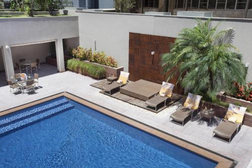 a swimming pool with lounge chairs and a table at Windsor Plaza Brasilia in Brasilia