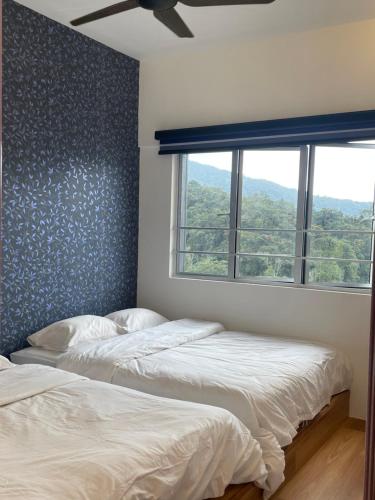 two beds in a bedroom with a window at Cameron Homestay Adik Aisyah Purple Romance for Islam in Tanah Rata