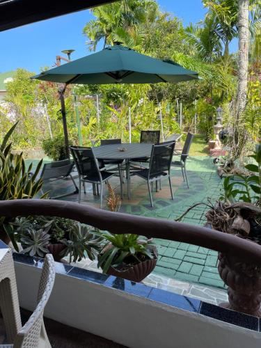 a patio with a table and chairs and an umbrella at Orchid Sunset Guest House in Baie Lazare Mahé