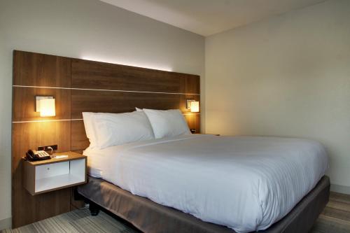 a hotel room with a large bed and a night stand at Holiday Inn Express & Suites Wapakoneta by IHG in Wapakoneta