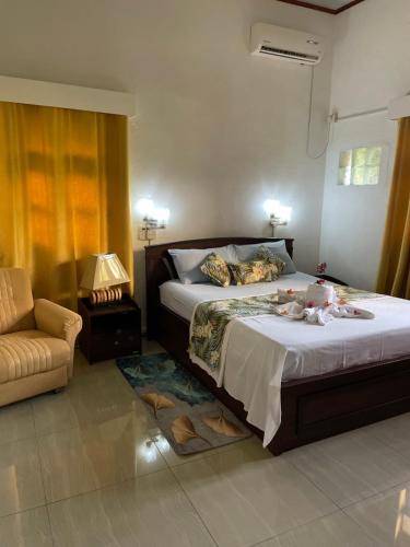 1 dormitorio con 1 cama, 1 silla y 1 sofá en Orchid Sunset Guest House en Baie Lazare Mahé