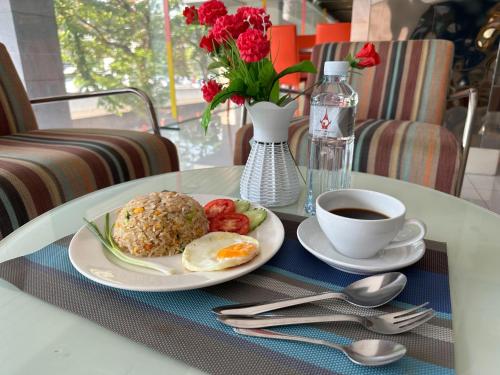 a table with a plate of food and a cup of coffee at Grand Tower Inn Sathorn Hotel in Bangkok