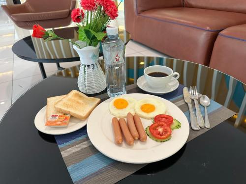 a table with two plates of breakfast foods and a cup of coffee at Grand Tower Inn Sathorn Hotel in Bangkok