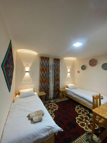 a hotel room with two beds and a table at Naqqosh in Khiva