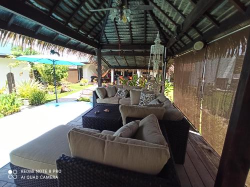 an outdoor patio with couches and an umbrella at La Maison Du Voyage in Tevaitoa
