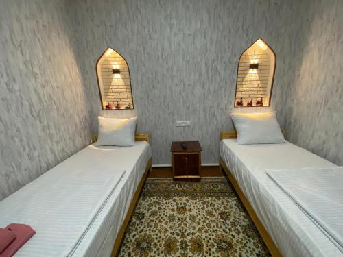 two beds in a room with two windows at Naqqosh in Khiva