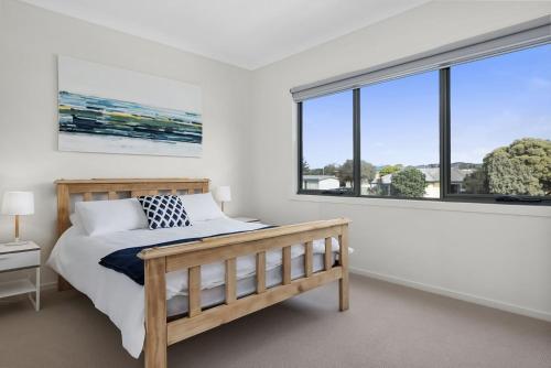 a bedroom with a bed and two windows at Glas in Apollo Bay
