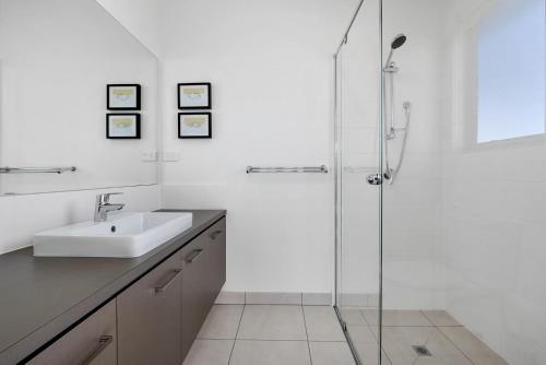 a white bathroom with a sink and a shower at Glas in Apollo Bay