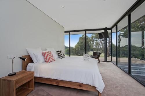 a bedroom with a large bed and large windows at Cypress Hill in Apollo Bay