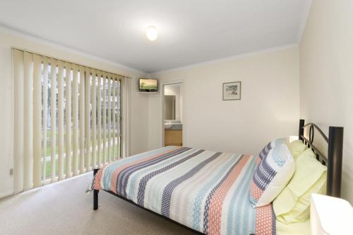 a bedroom with a bed and a large window at The Boulevard in Lorne
