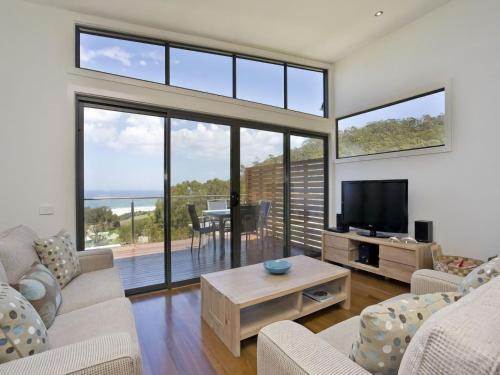 a living room with a tv and large windows at Earth Sea Sky in Wye River