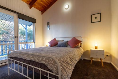 um quarto com uma cama com uma mesa de cabeceira e uma janela em The Albatross em Port Campbell