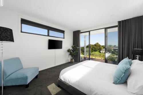 a bedroom with a white bed and a blue chair at Scenic Estate in Apollo Bay