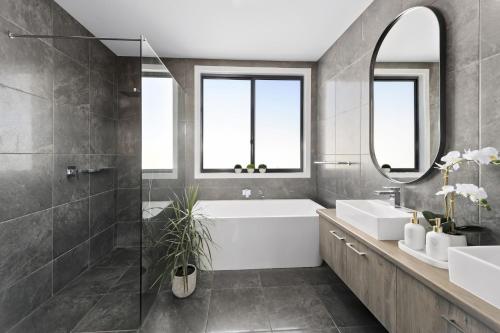 a bathroom with a tub and a sink and a mirror at Scenic Estate in Apollo Bay