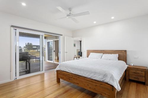 a white bedroom with a bed and a sliding glass door at Aurora in Apollo Bay