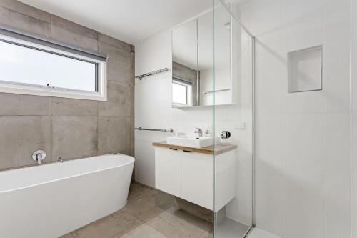 a white bathroom with a tub and a sink at Aurora in Apollo Bay