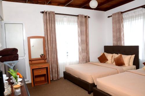 a hotel room with two beds and a mirror at The Fern Inn in Nuwara Eliya