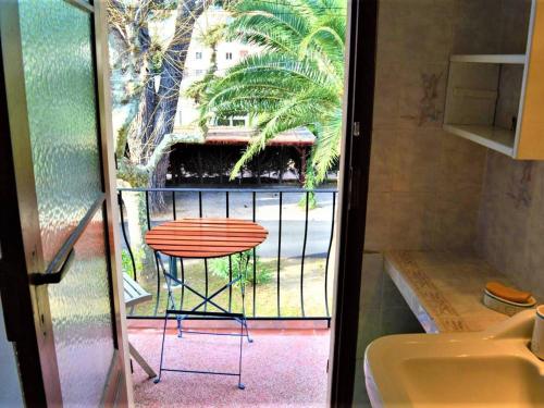 d'un balcon avec une table et une vue sur un palmier. dans l'établissement Appartement 2 pièces avec terrasse, proche plage et centre-ville à Cavalaire-sur-Mer, parking inclus - FR-1-226B-19, à Cavalaire-sur-Mer