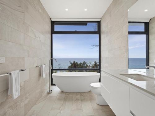 a bathroom with a tub and a toilet and a window at Iluka Blue in Wye River