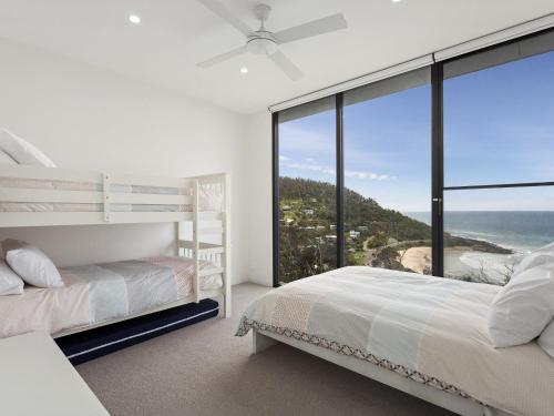 a bedroom with two beds and a large glass window at Iluka Blue in Wye River