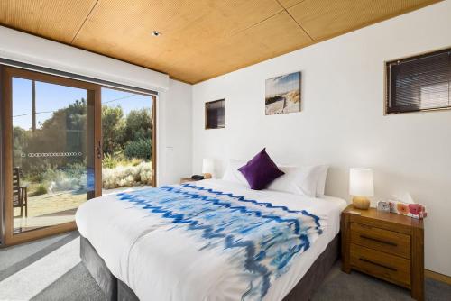 a bedroom with a large bed and a large window at Manta Ray One in Apollo Bay