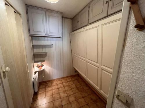 Elle comprend une petite cuisine avec des placards blancs et du carrelage. dans l'établissement Appartement Cavalaire-sur-Mer, 1 pièce, 4 personnes - FR-1-226B-116, à Cavalaire-sur-Mer