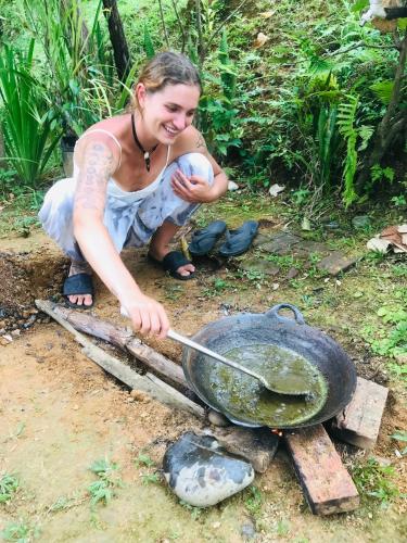 a woman is cooking food in a wok at Sumatra Thomas Leaf Monkey Guesthouse & Jungle Trek in Bukit Lawang