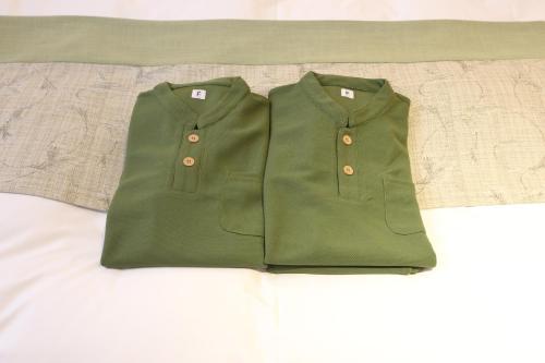 two green shirts sitting on top of a bed at Hotel Naranohamori in Nara