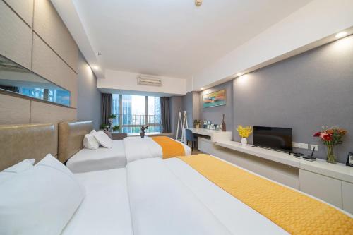 a bedroom with two white beds and a television at Orange Tree International Hotel Zhujiang New Town US Consulate General Guangzhou Branch - Free Shuttle Bus to Canton Fair Complex During Canton Fair Period in Guangzhou