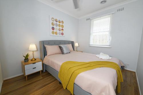 a bedroom with a bed with a yellow blanket on it at Pet-friendly Bayside 4BR Rental House near Mentone in Parkdale