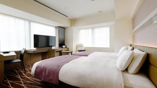 Habitación de hotel con cama, escritorio y TV. en remm plus Ginza, en Tokio
