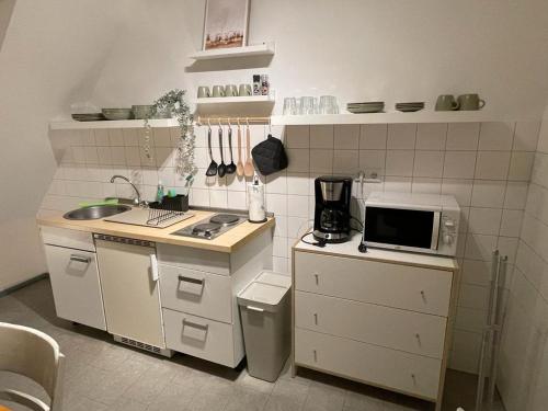 una pequeña cocina con fregadero y microondas en Budgethotel Stadtbett Wolfsburg, en Wolfsburg