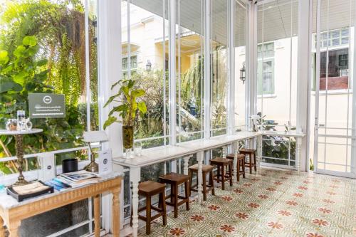 a lobby with chairs and tables and windows at Baan 2459 Heritage House in Bangkok