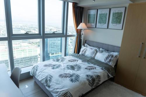 a bedroom with a bed in a room with windows at A2J Luxury 2BR BGC Uptown Suite Near Uptown Mall in Manila
