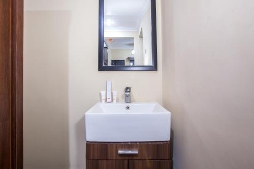a bathroom with a white sink and a mirror at Capital O 887 Green Hill Hotel And Convention Center in Jember