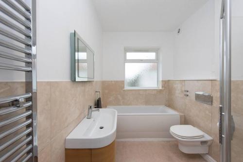 ein Badezimmer mit einem Waschbecken, einem WC und einer Badewanne in der Unterkunft Five-bedroom house at Margate, near beach and amenities in Margate