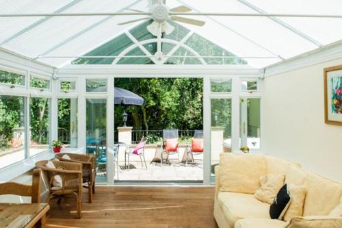 a living room with a conservatory with a ceiling fan at Acorns with own hot tub, romantic escape, close to Lyme Regis in Uplyme
