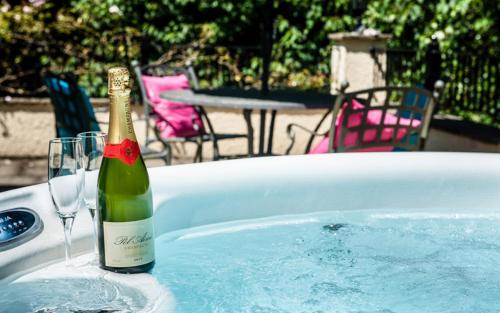 Uplyme的住宿－Acorns with own hot tub, romantic escape, close to Lyme Regis，一瓶香槟和浴缸内的一杯