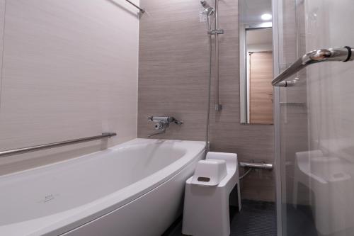 a white bathroom with a tub and a toilet at Hotel Vista Hiroshima in Hiroshima