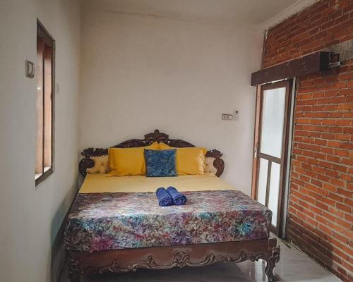 a bed in a room with a brick wall at Notojiwo Private House 2 rooms in Jarakan