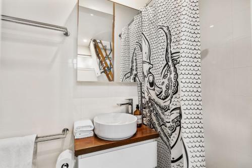 uma casa de banho branca com um lavatório e um chuveiro em Daybreak Loft em Gold Coast