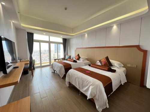 a hotel room with two beds and a flat screen tv at Wenchang Waika Hotel in Wenchang