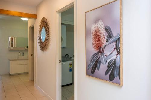 baño con una foto de una flor en la pared en 1 Bright Point Apartment 1307, en Nelly Bay