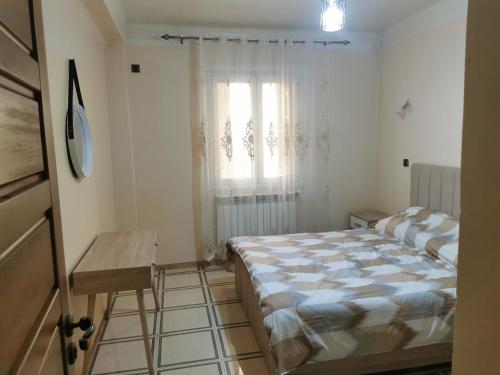 a bedroom with a bed and a window and a table at Appartement F4 de Luxe in Constantine