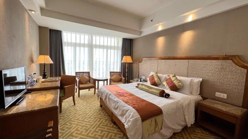 a hotel room with a large bed and a desk at Wenchang Waika Hotel in Wenchang