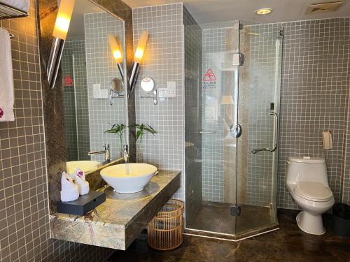 a bathroom with a sink and a shower and a toilet at Wenchang Waika Hotel in Wenchang