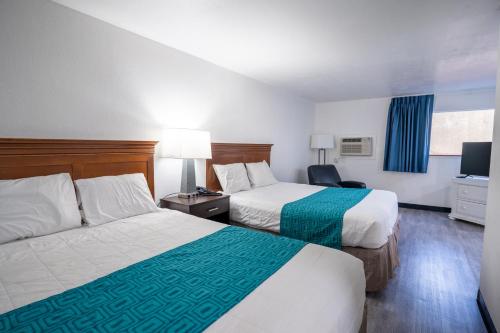 um quarto de hotel com duas camas e uma televisão em Kennewick Inn & Suites Tri Cities em Kennewick