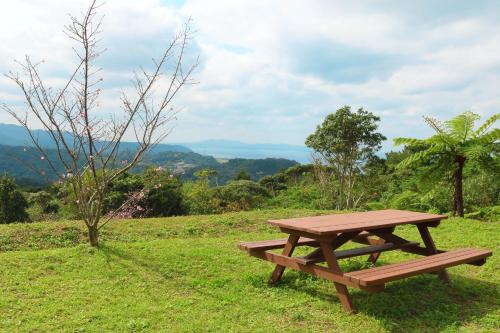 un tavolo da picnic in legno, posto in cima a un campo di Hija on the Hill -SEVEN Hotels and Resorts- a Kunigami