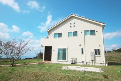 a white house on a grassy field at Hija on the Hill -SEVEN Hotels and Resorts- in Kunigami